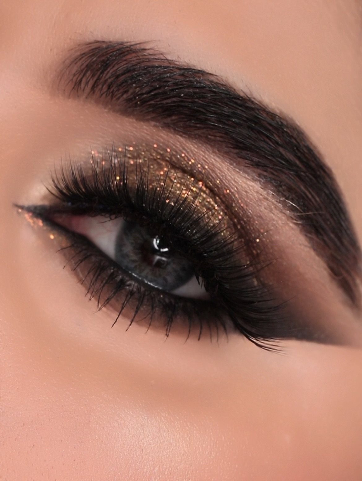 Blue eye with shimmering bronze smoky eyeshadow and long black eyelashes.