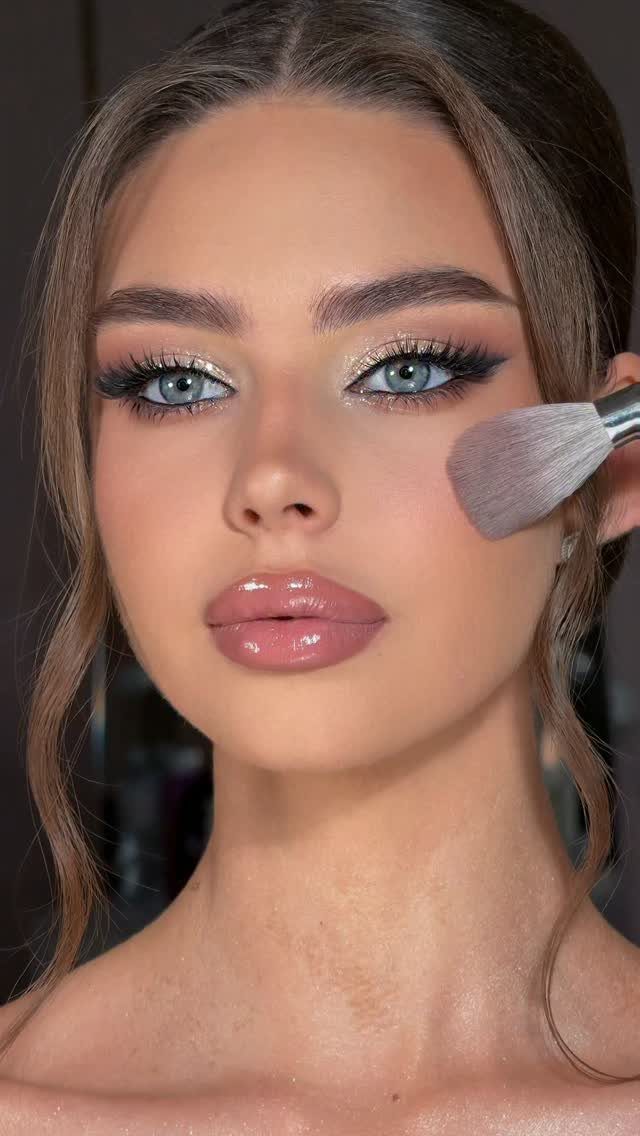 Woman with blue eyes wearing shimmering gold wedding makeup and glossy pink lips