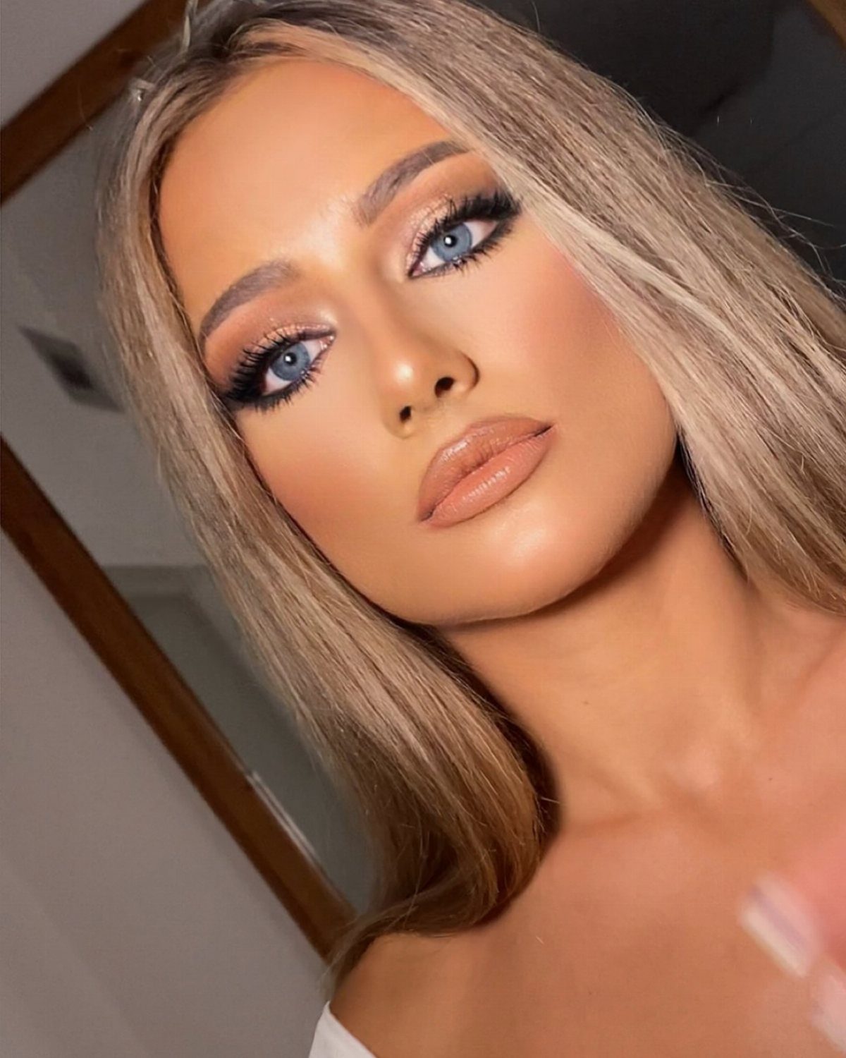 Woman with blue eyes wearing warm peach and bronze eyeshadow and nude lipstick.