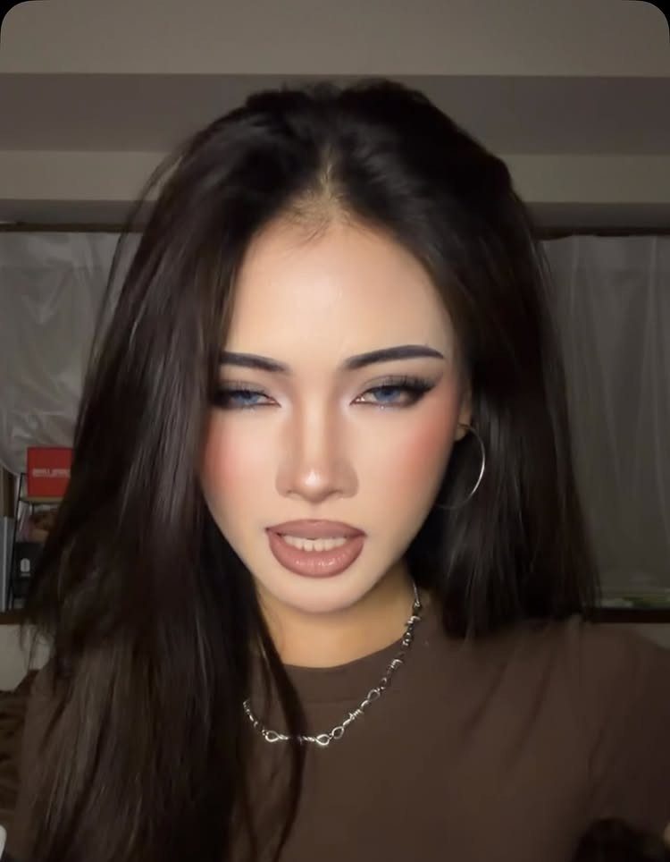 Woman with blue eyeshadow and glossy lips posing for a y2k makeup portrait