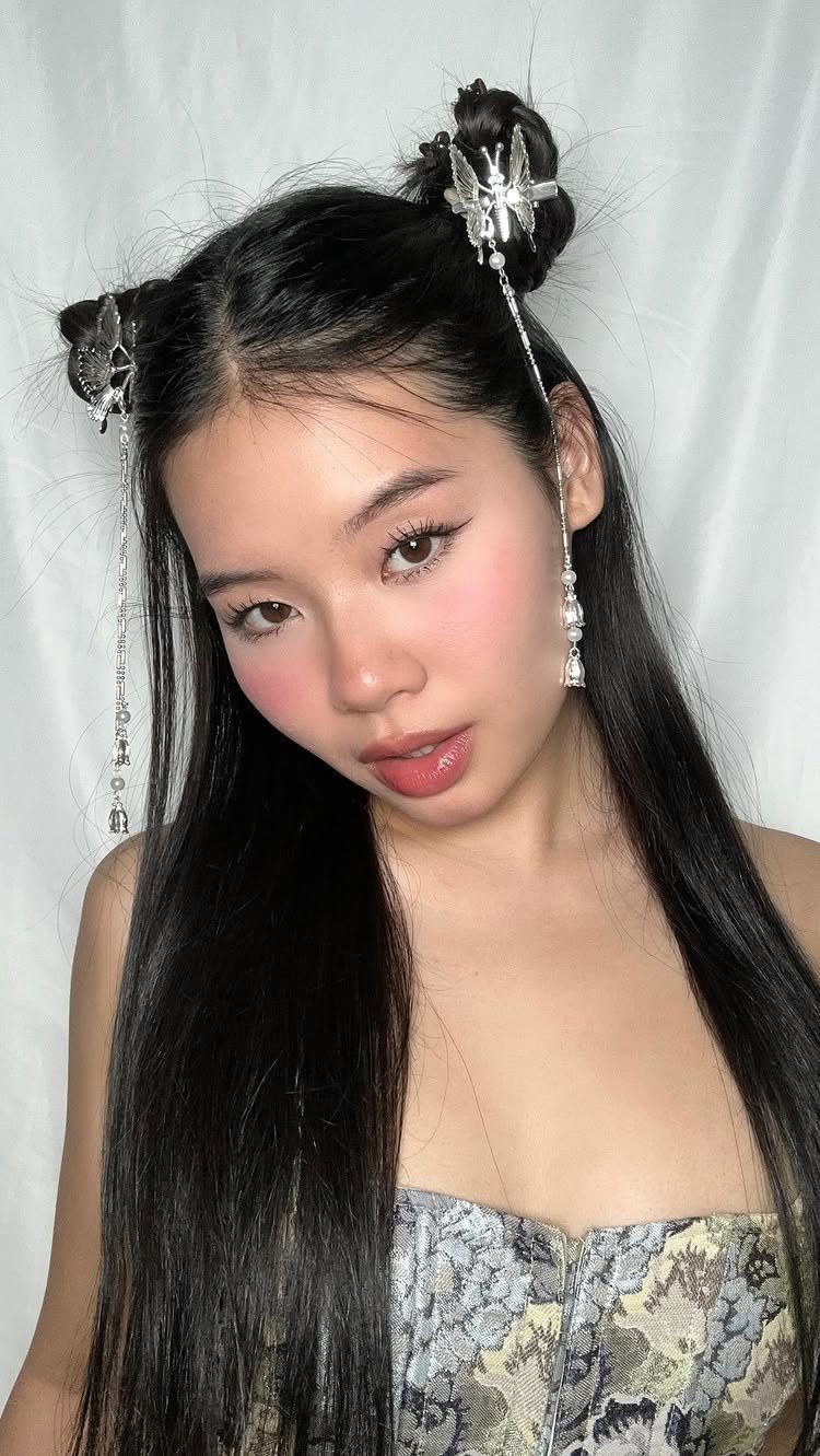 Woman with black hair in buns featuring silver butterfly clips and hanging chains.
