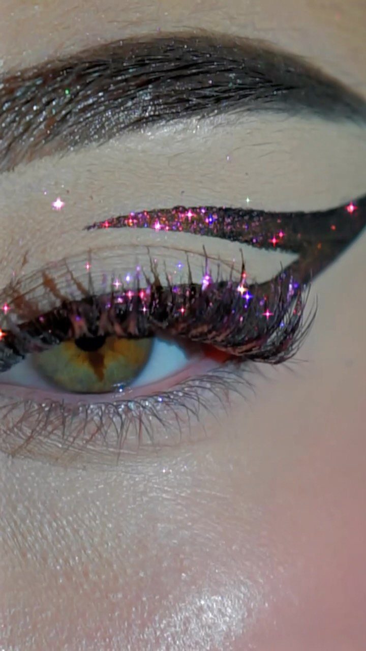 Eye with bold purple glitter graphic eyeliner and long dramatic false eyelashes